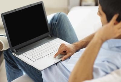 Un homme utilise son ordinateur portable sur le canapé.