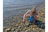 Enfant ramassant des roches le long du rivage.