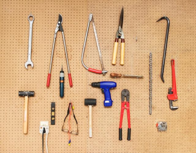 Un assortiment d'outils suspendus sur panneau perforé.