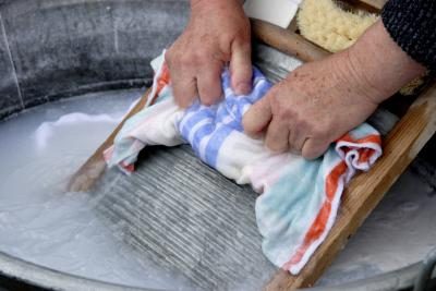 Femme utilisant une planche à laver pour nettoyer les vêtements.
