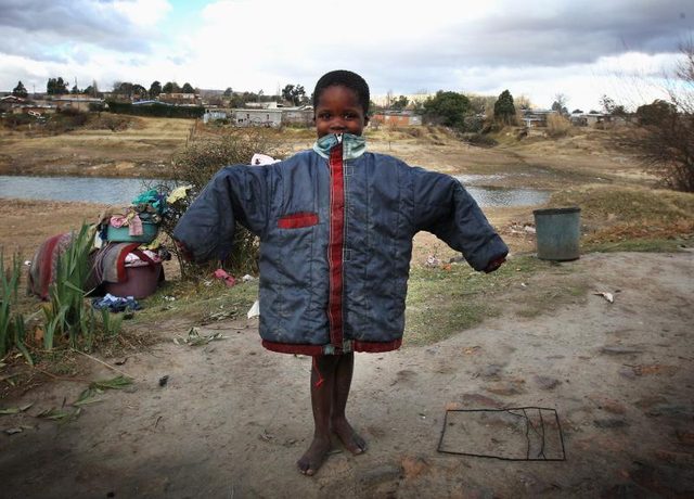 Un jeune orphelin tenant un manteau don.
