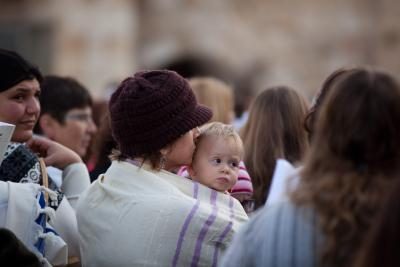 Femme portant un châle tient son bébé au Mur des Lamentations