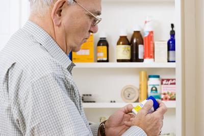 Homme adulte lit les étiquettes des médicaments pour voir quel médicament anti-inflammatoire conviendra mieux