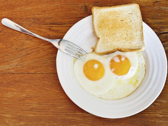 Plaque avec deux œufs et morceau de blanc toast de pain.