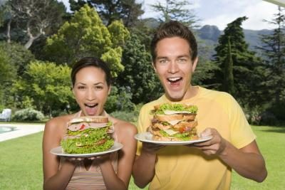 l'homme et la femme tenant des sandwichs géants