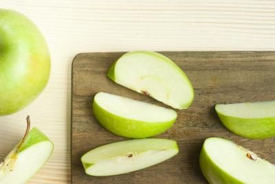 Tranches de pommes vertes sur une planche à découper en bois.