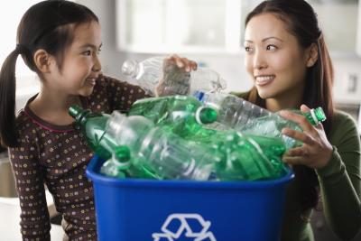 Une mère et sa fille utilisent un bac de recyclage.