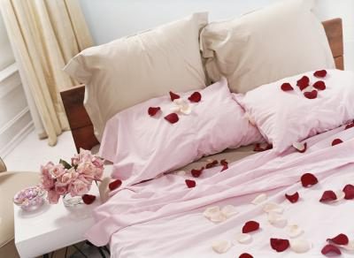 Pétales de rose sur le lit va créer une ambiance romantique.