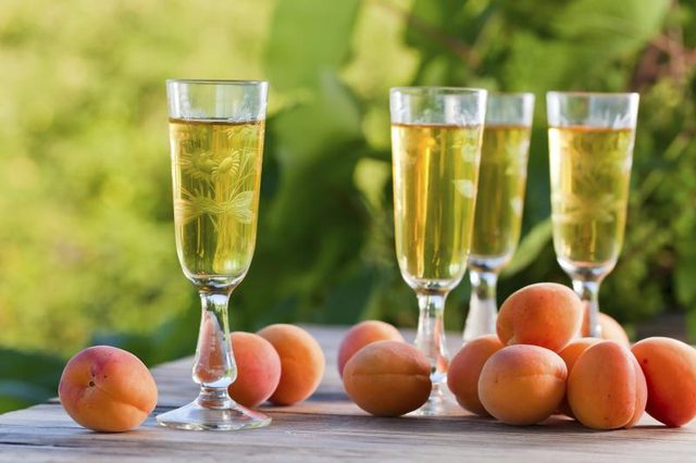 Verres de vin de dessert sur une table en plein air avec des abricots frais.