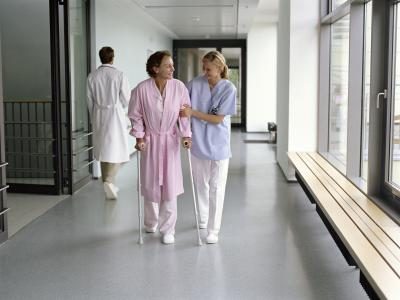 Une infirmière se promène avec un patient en bas d'une corrider dans un hôpital.