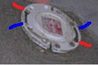 Close up de la bride de toilette. Insérez les boulons de la toilette dans les marques rouges et les déplacer vers les marques bleues. Retirer le disque centre de plastique avec un marteau.