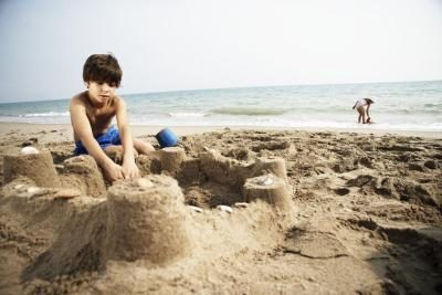 Jeune garçon construire un château de sable sur la plage.