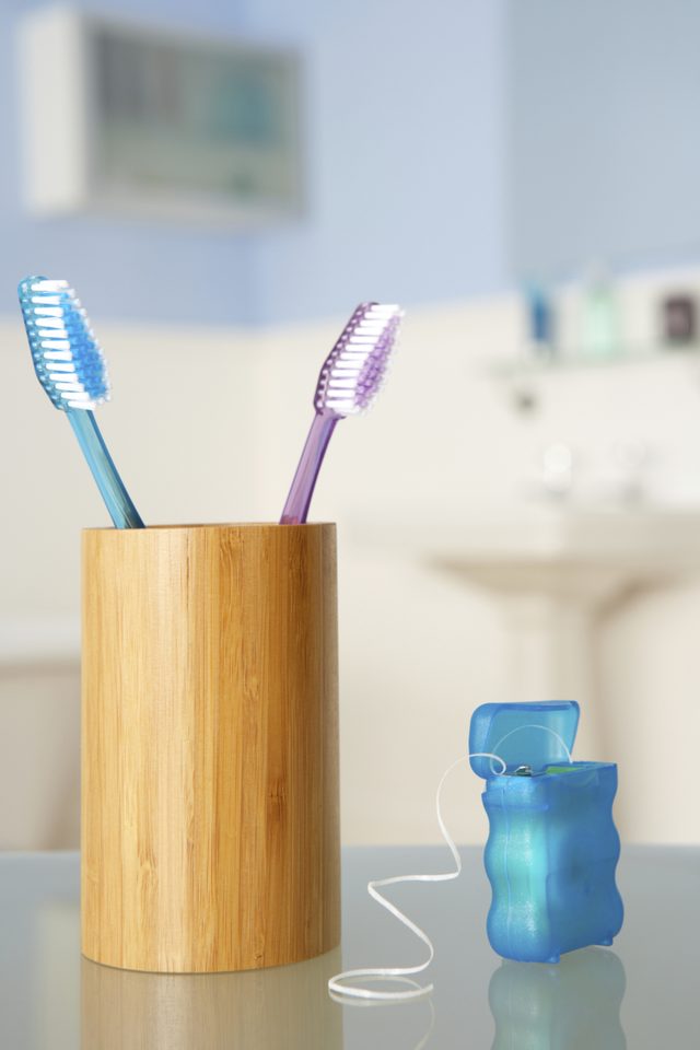 Un gros plan de la soie dentaire à côté d'un porte brosse à dents.