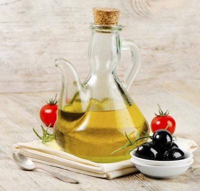 Une bouteille d'huile d'olive avec un quelques olives noires et tomates