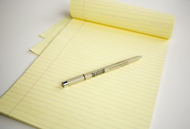Un gros plan d'un stylo à l'encre sur un bloc de papier.