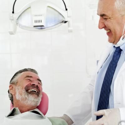 Un dentiste rires avec son patient.