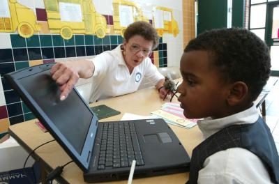 Une femme montre un jeune garçon comment utiliser l'ordinateur.