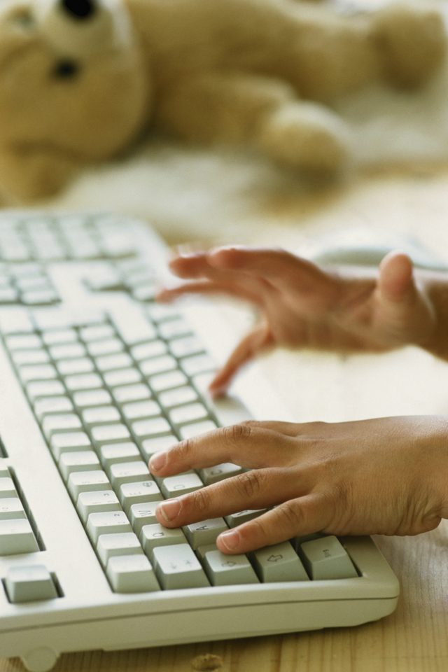 Un gros plan d'un enfant's hands on a computer keyboard.
