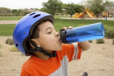 Un garçon boit de l'eau alors qu'il circulait à vélo.