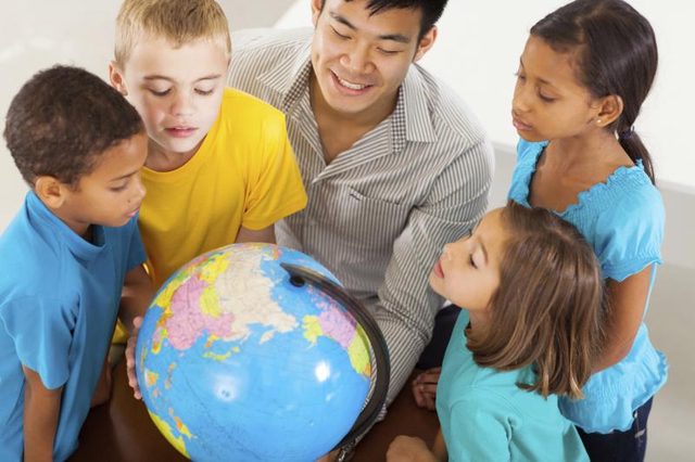 Les jeunes élèves et leurs enseignants qui cherchent à globes.